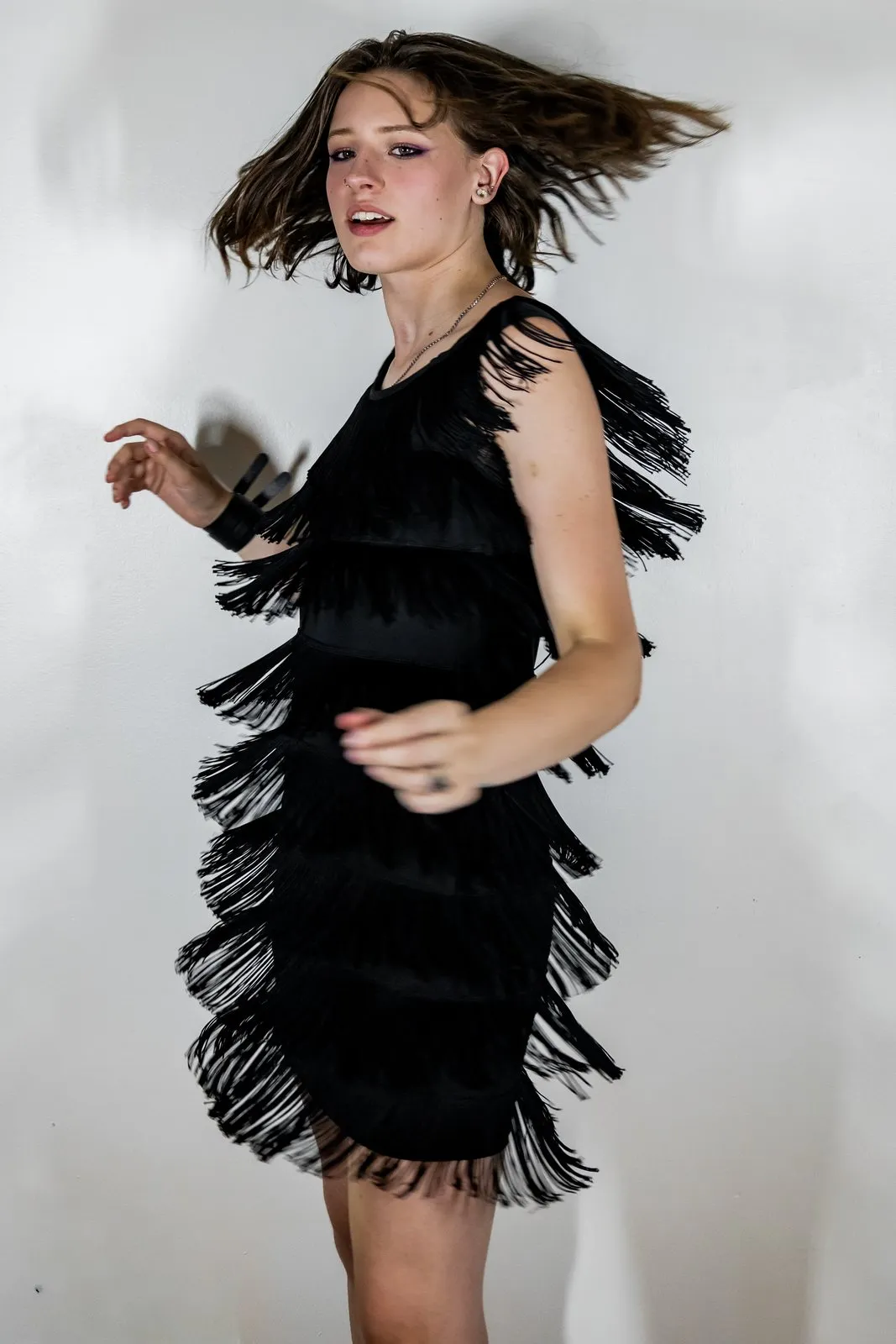 Black dress caught mid-movement against a white wall