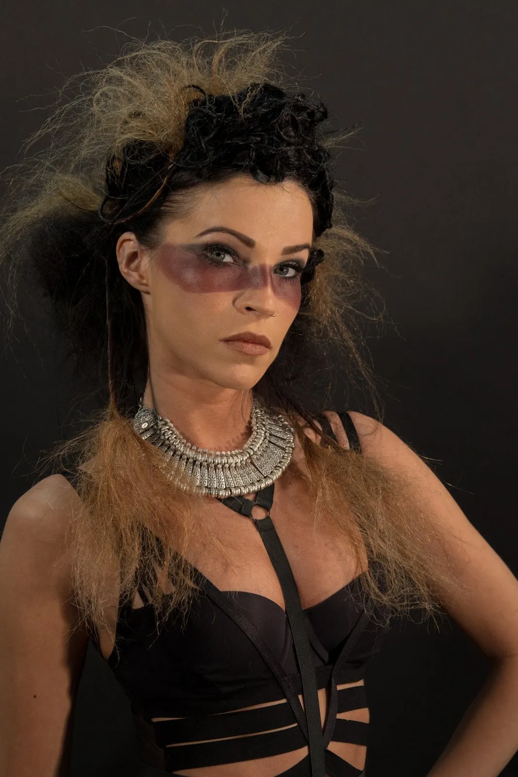Dark studio portrait with feathers and layered necklaces