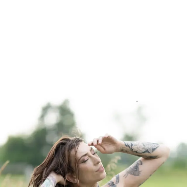 In a field, arms raised in soft light